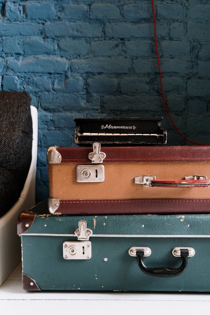 Stack of vintage suitcases against a rustic blue brick wall, ideal for travel themes.
